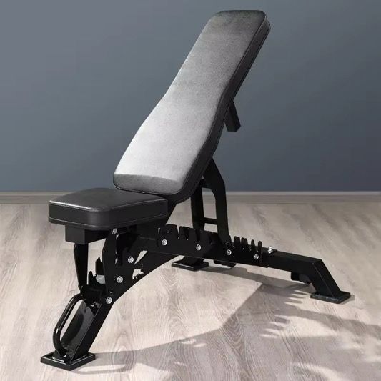 Adjustable weight bench on a wooden floor with a gray wall background
