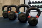 Set of black kettlebells with weight markings on a dark surface.