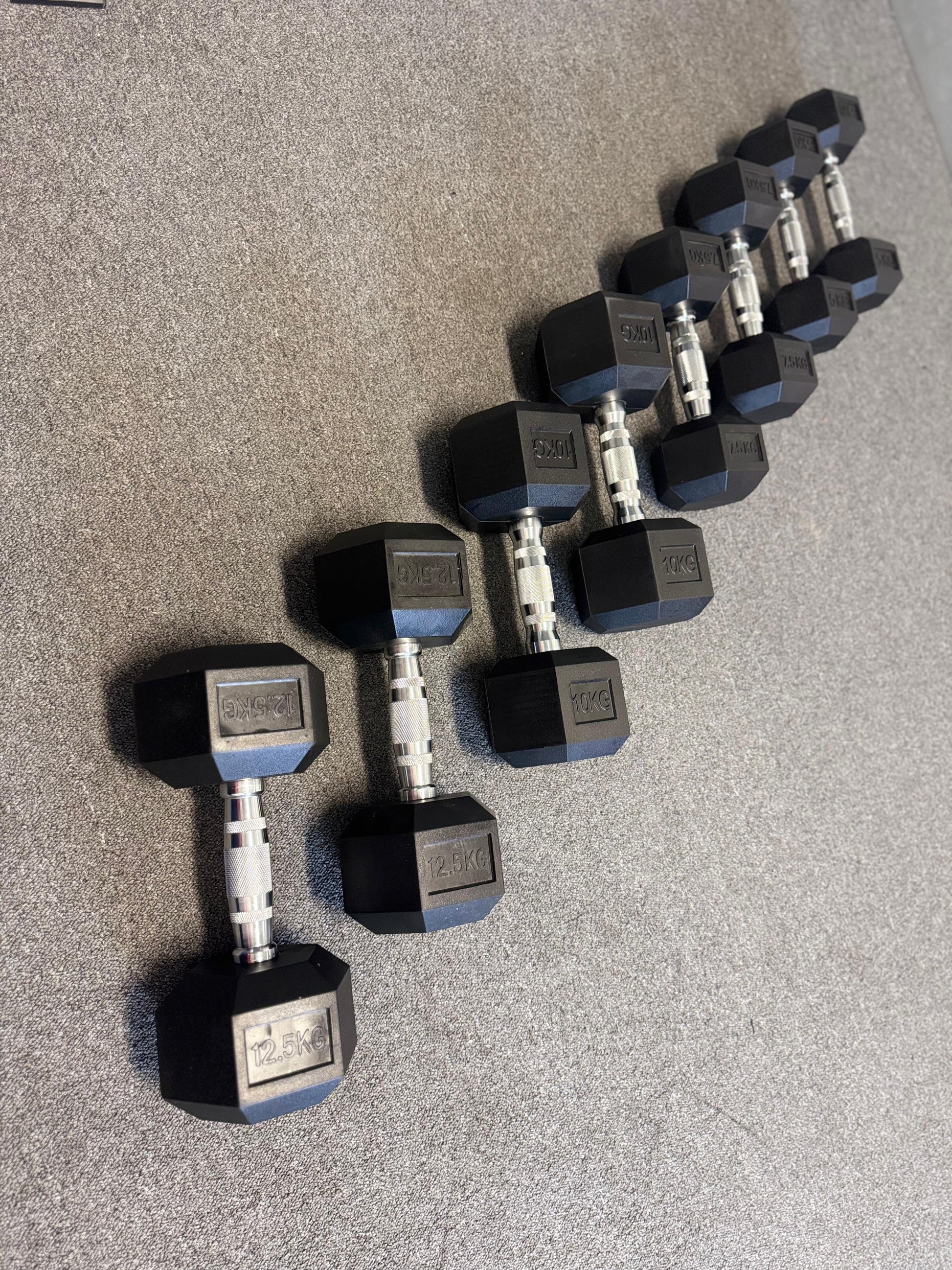 Set of hexagonal dumbbells on a gray floor