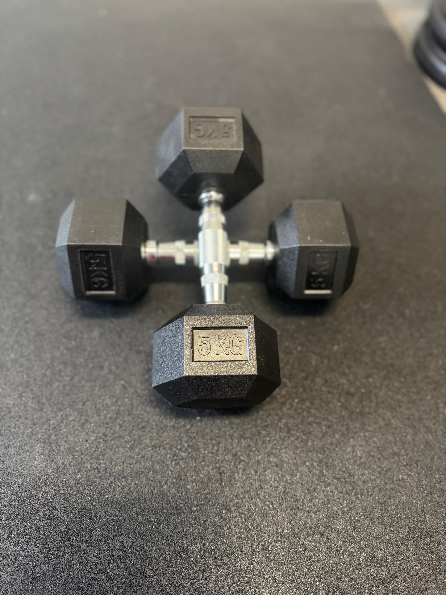 Pair of black dumbbells with '5 KG' marking on a gray surface