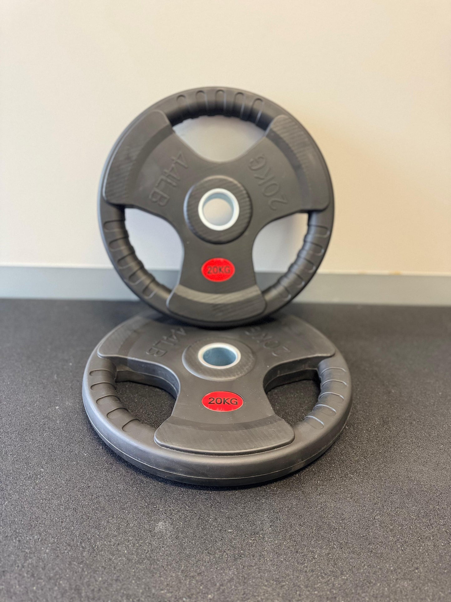 Two gray weight plates with red logos on a gray surface.