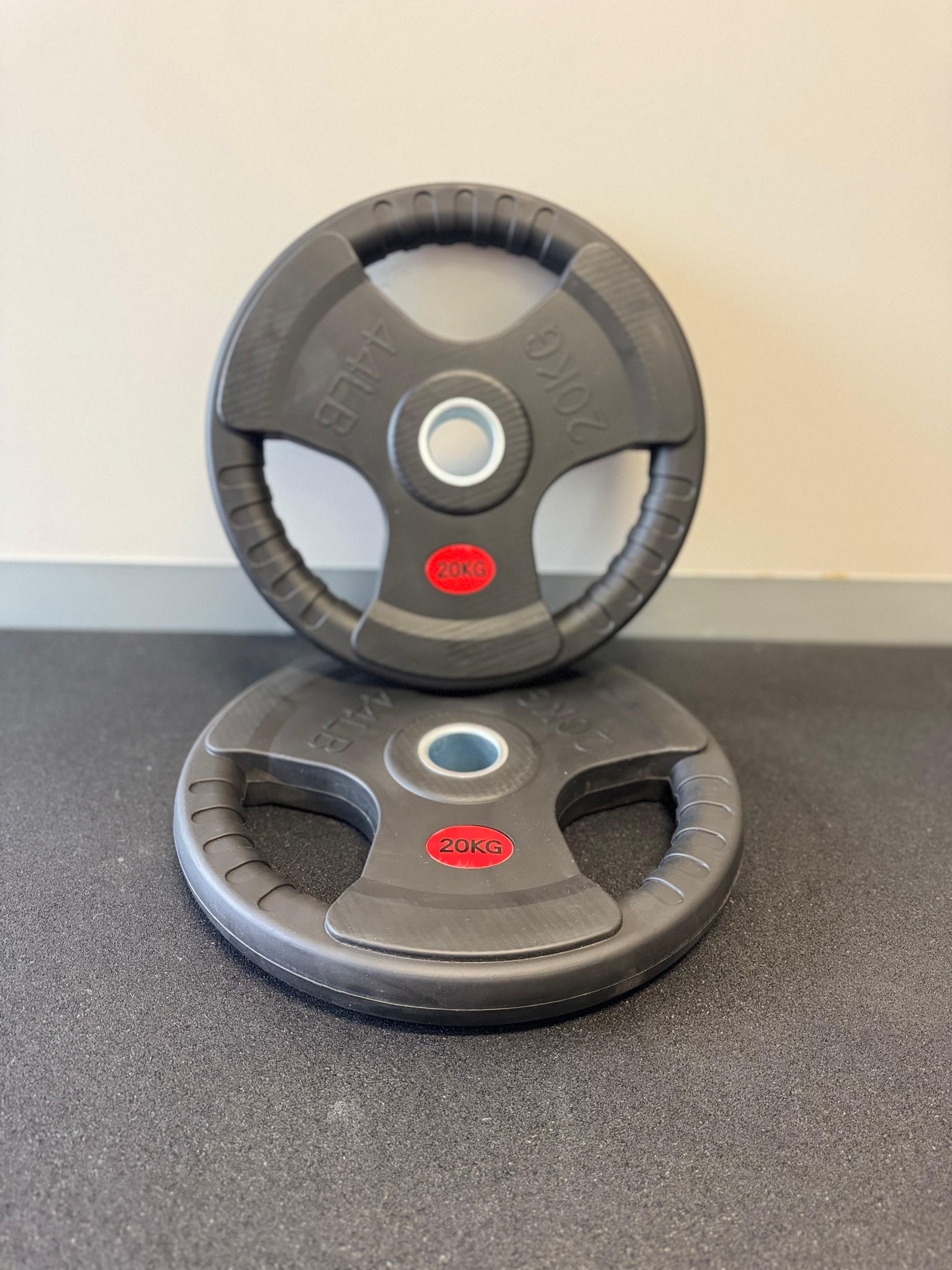 Two gray weight plates with red logos on a gray surface.