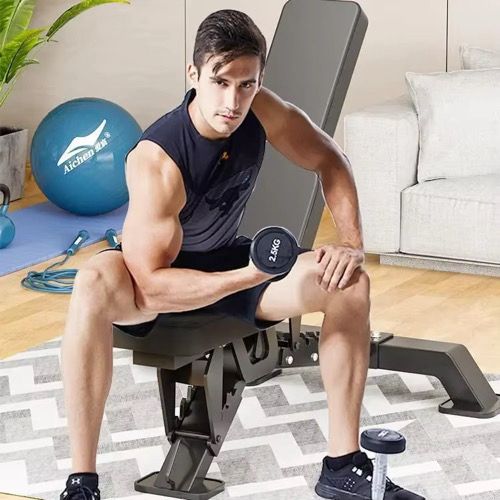 Man exercising with dumbbells on a weight bench in a home setting